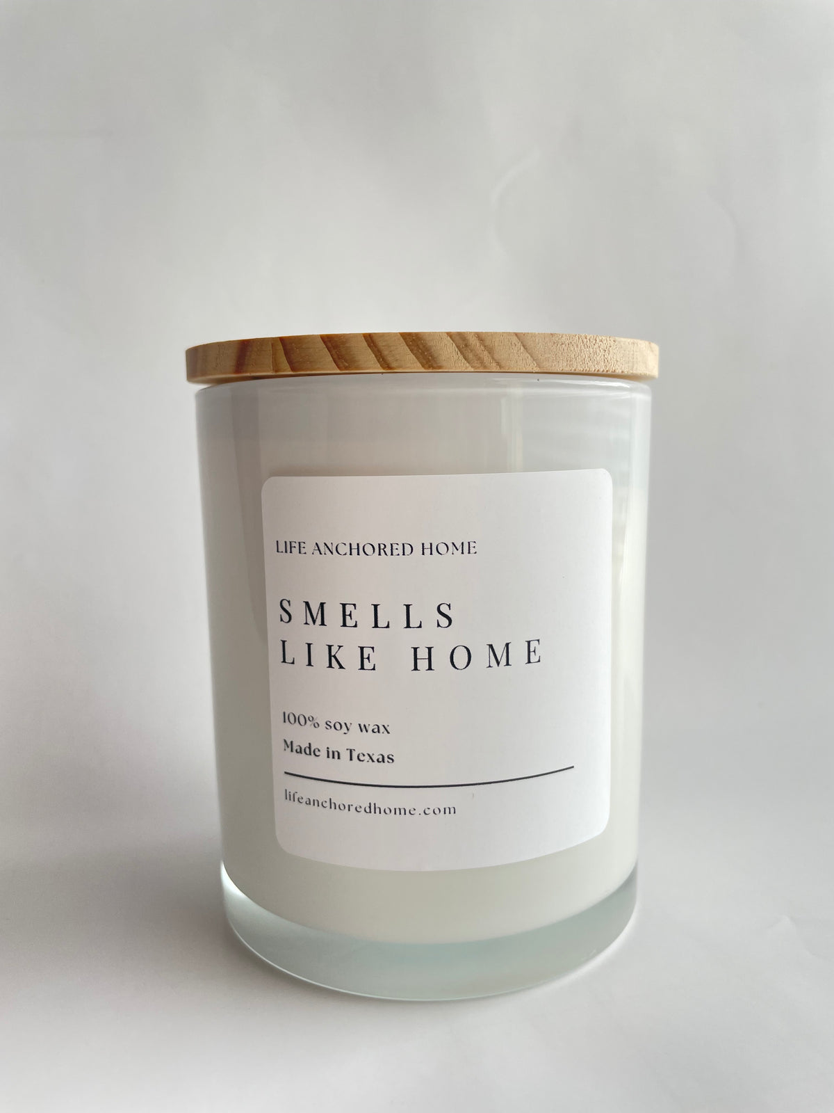 Candle with a label reading 'Smells Like Home' on a light gray background