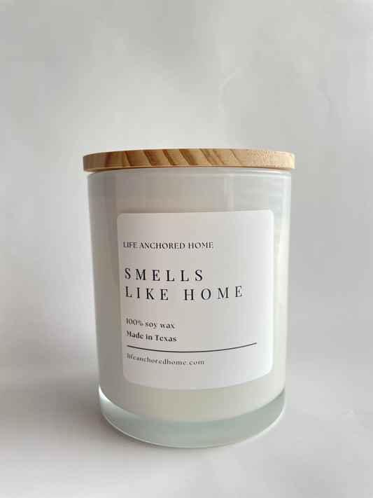 Candle with a label reading 'Smells Like Home' on a light gray background